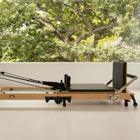 Black FOLD Reformer bed laid out flat with background window of trees