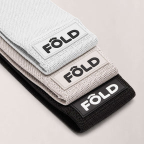 Pilates Resistance Bands Bundle - White, Timber wolf Grey, Black in a stacked arrangement showcasing their vibrant colors.