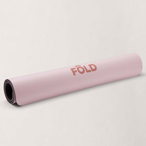 FOLD Reformer Pilates Mat - Pink rolled up on a light background, showcasing its soft cushioning and durability.