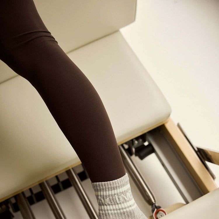 Leg on beige footbar of FOLD Reformer bed