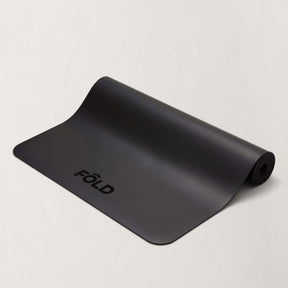 FOLD Yoga Mat - Black displayed on a neutral background, showcasing its sleek design and grip surface for workouts.