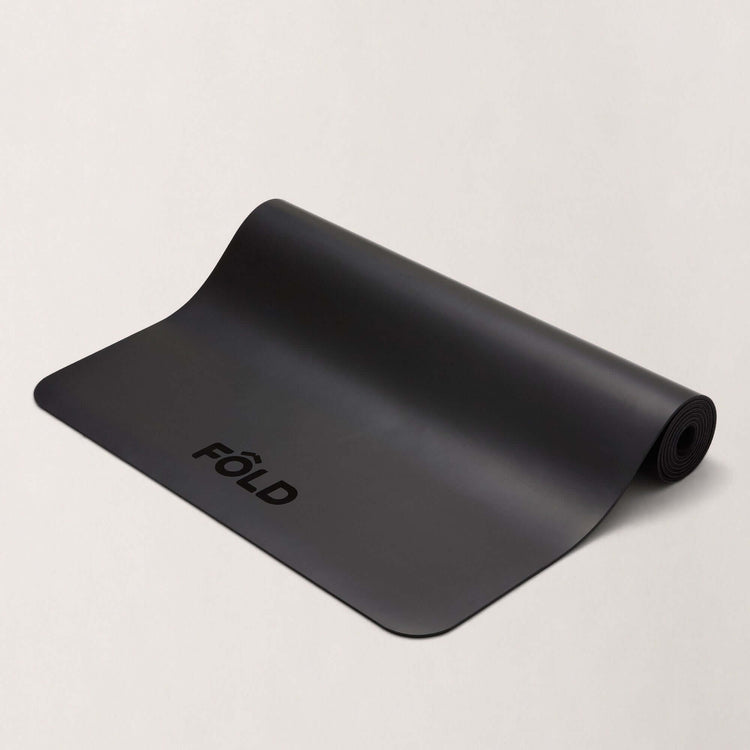 FOLD Yoga Mat - Black displayed on a neutral background, showcasing its sleek design and grip surface for workouts.