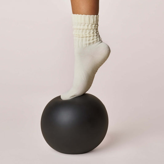 Close-up of a foot wearing Pilates Scrunch Grip Socks - Off White on a black stability ball.