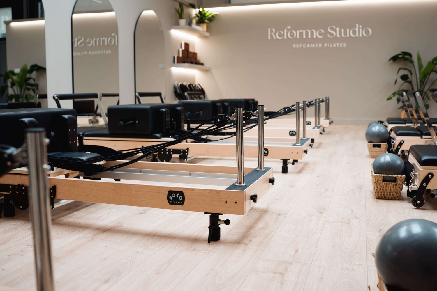 Pilates reformers lined up in a studio with 'Reforme Studio' branding.