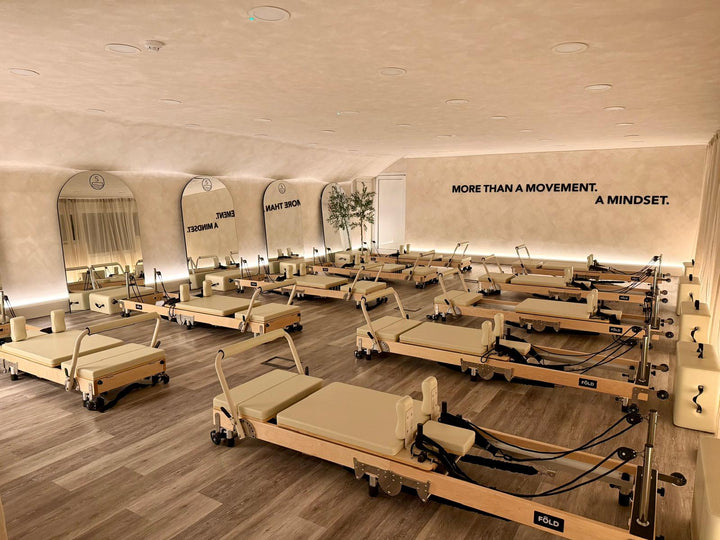 A spacious pilates studio with wooden reformers and motivational quotes on the wall, creating a calming environment.