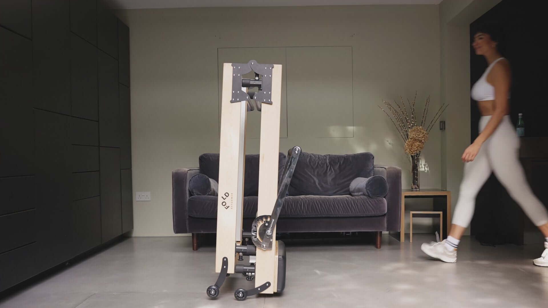 Folded Reformer bed women walking towards the bed in a living room 